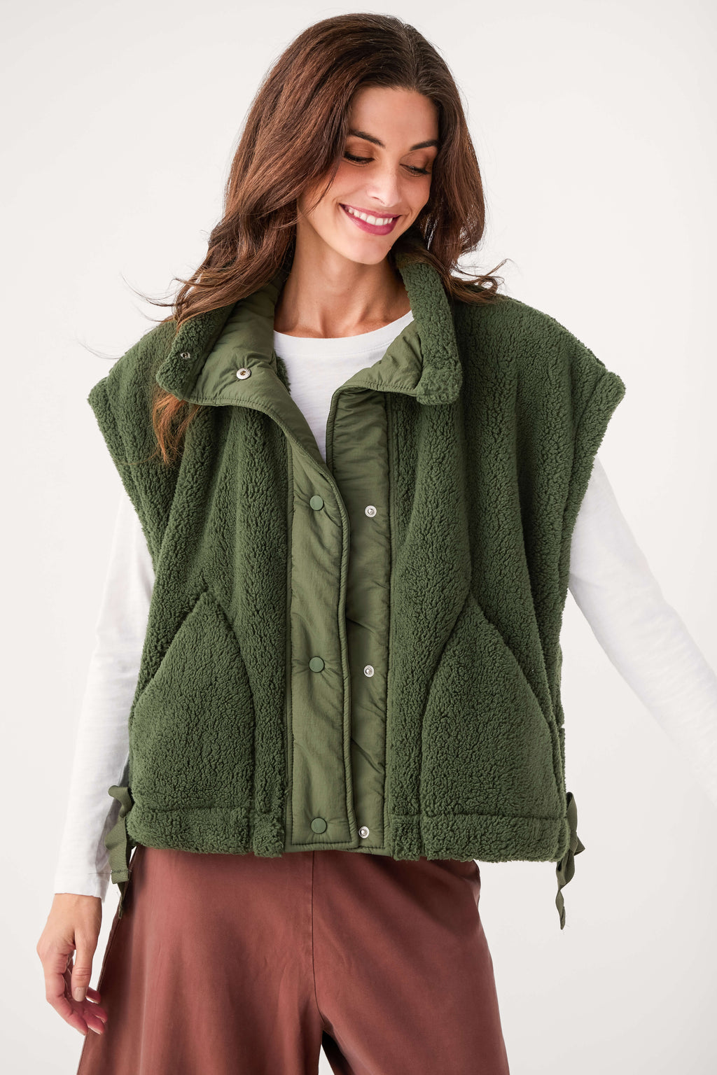 Dark green fleece vest with snap button front and stand collar, close-up with white top.