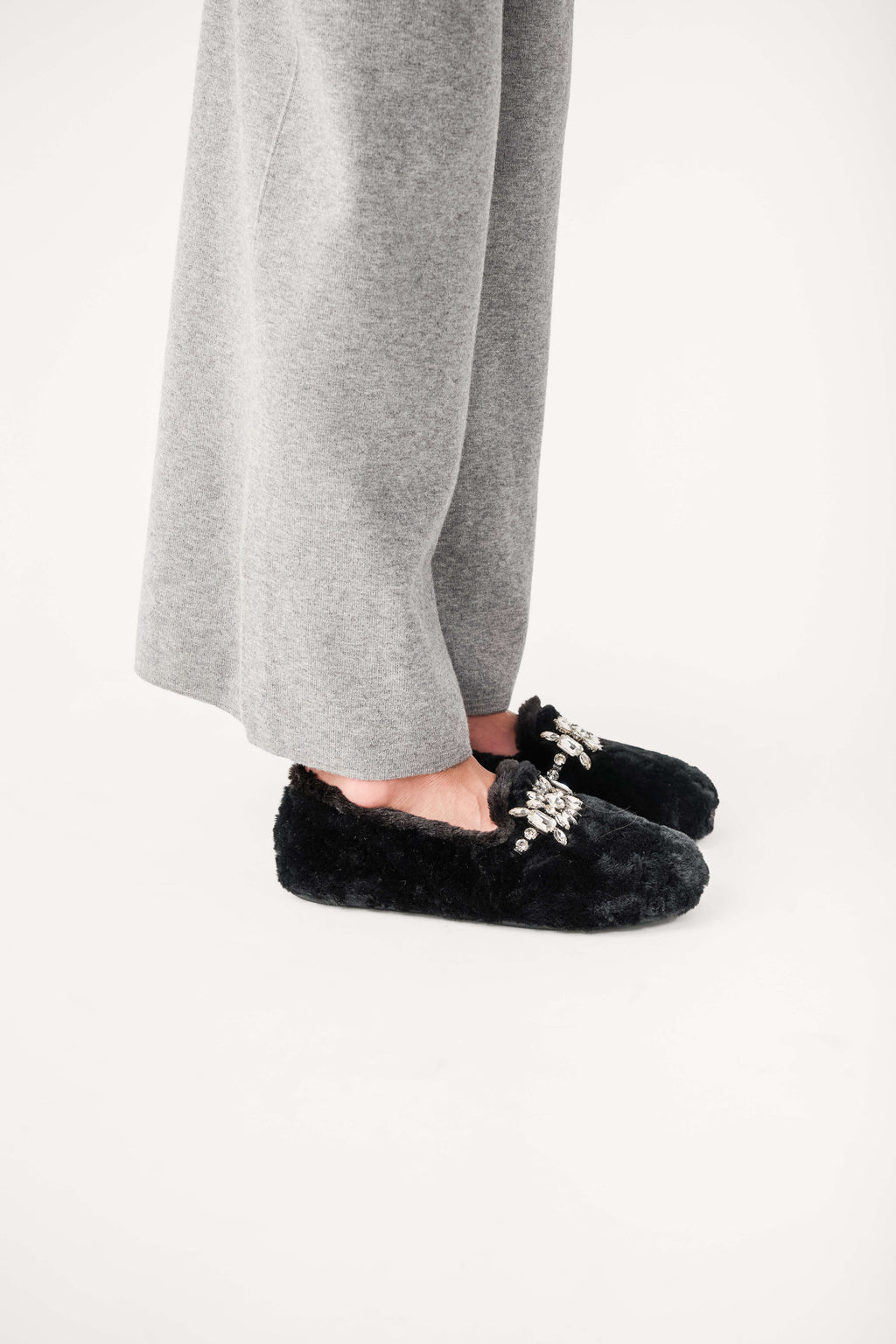 Black fuzzy slip-on loafers with jeweled floral applique on top