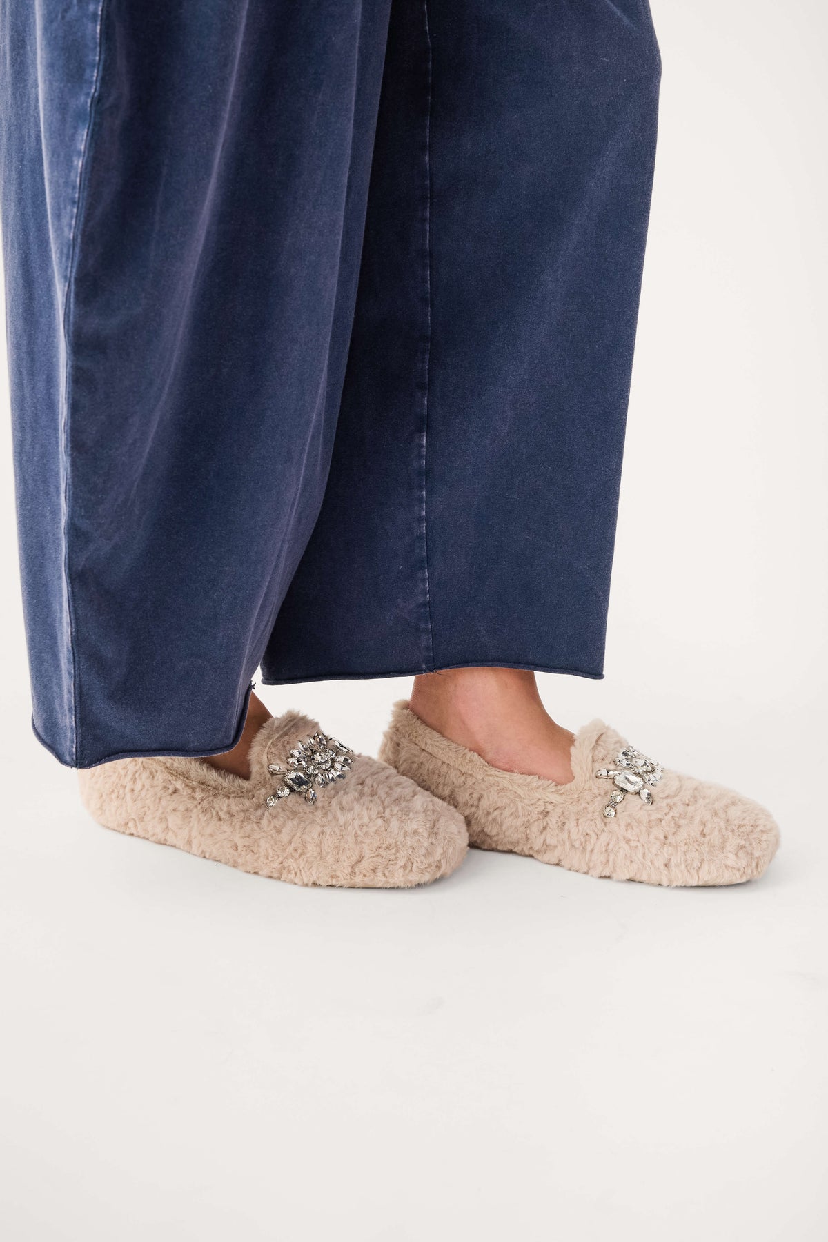 Beige fuzzy loafer slippers with jeweled floral applique on top and rounded toe