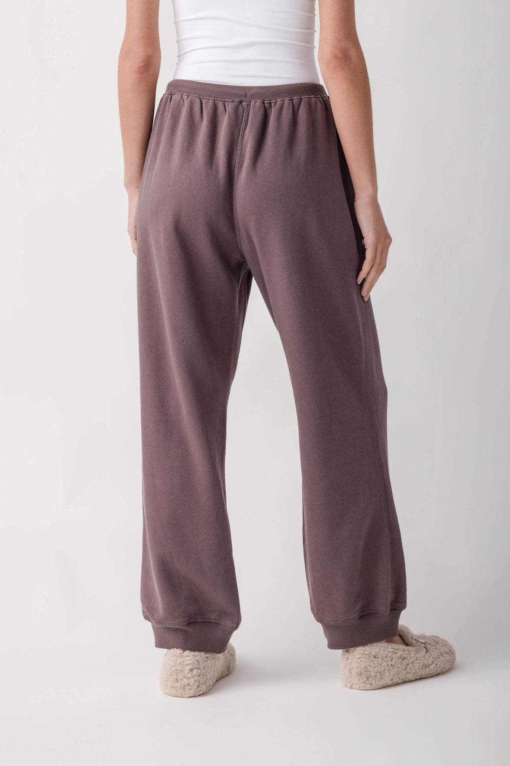Mauve joggers with ribbed waistband and cuffs, shown from behind on a model wearing a white tank top.