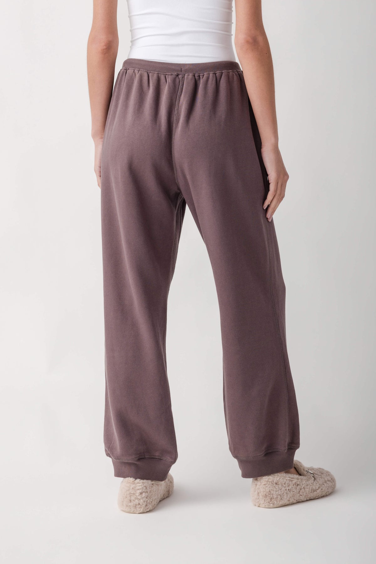 Mauve joggers with ribbed waistband and cuffs, shown from behind on a model wearing a white tank top.