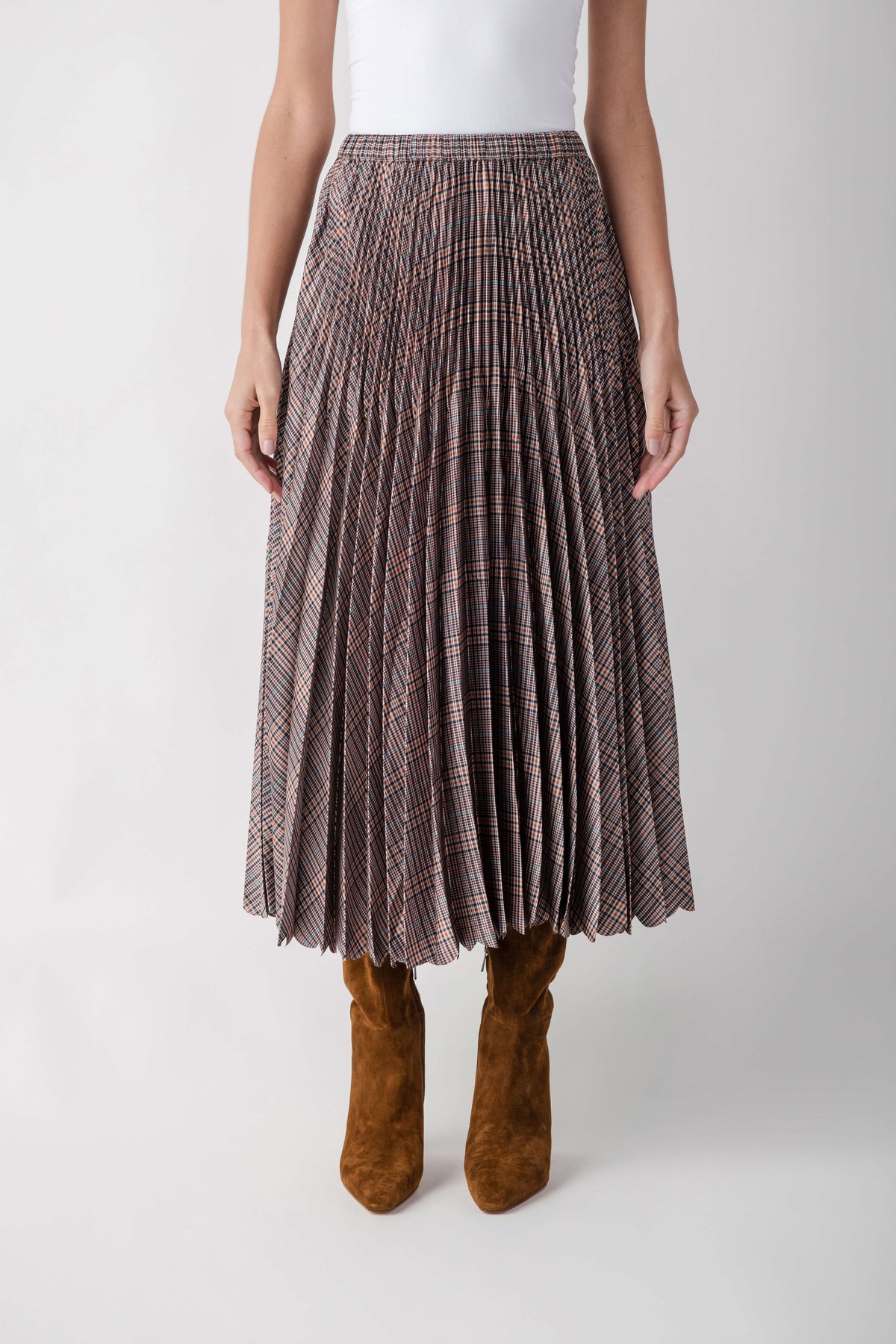 Plaid pleated maxi skirt in brown and navy tones with elasticized waistband, styled with brown suede boots.