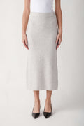 Cream ribbed knit midi skirt with elastic waistband worn with white tank top and black pointed heels.