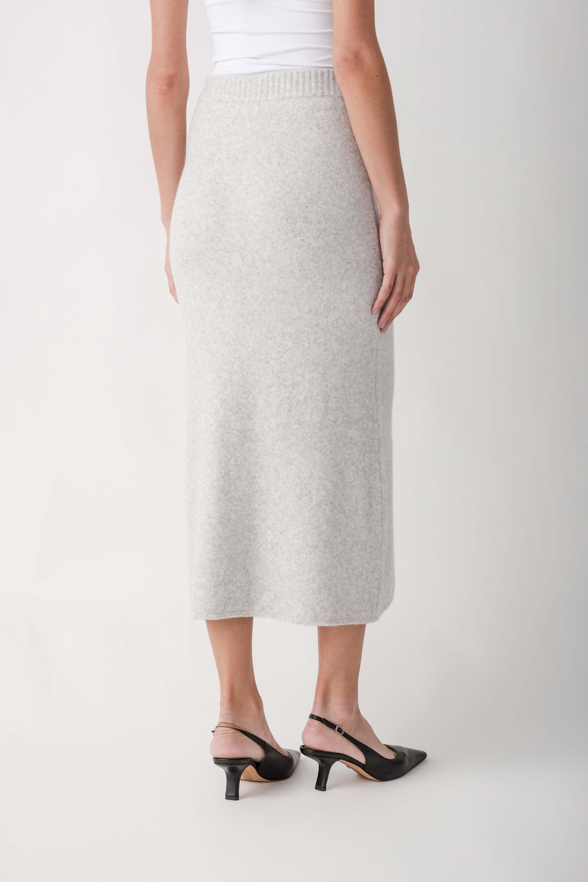 Cream ribbed midi skirt with elastic waistband worn with white tank top and black slingback heels.