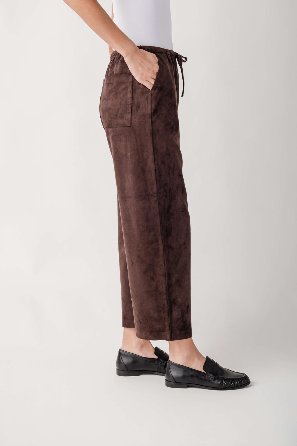 Brown suede pants with drawstring waist and front pockets, displayed on model wearing black loafers.