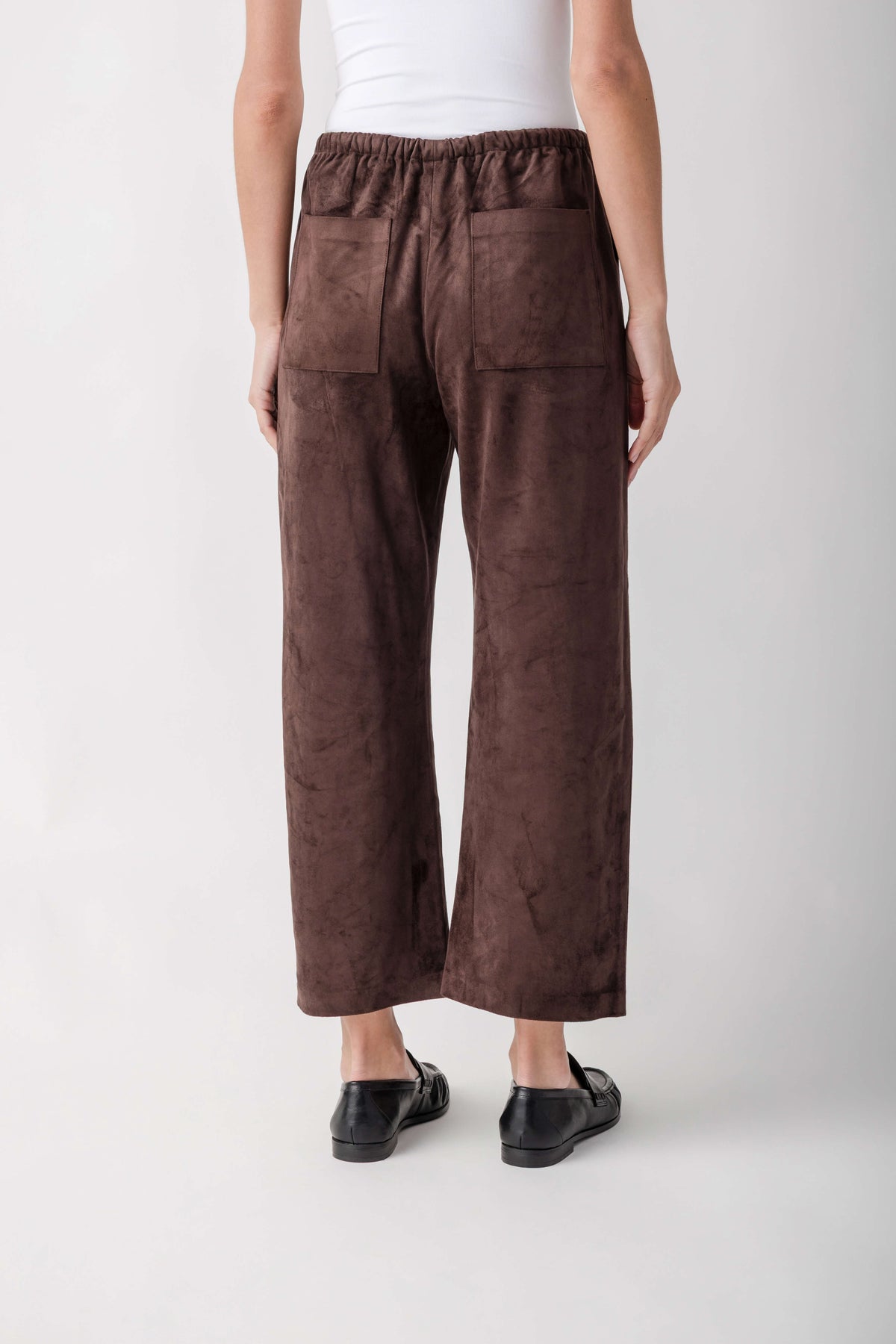Brown suede pants with elastic waistband and patch pockets, shown from back view.