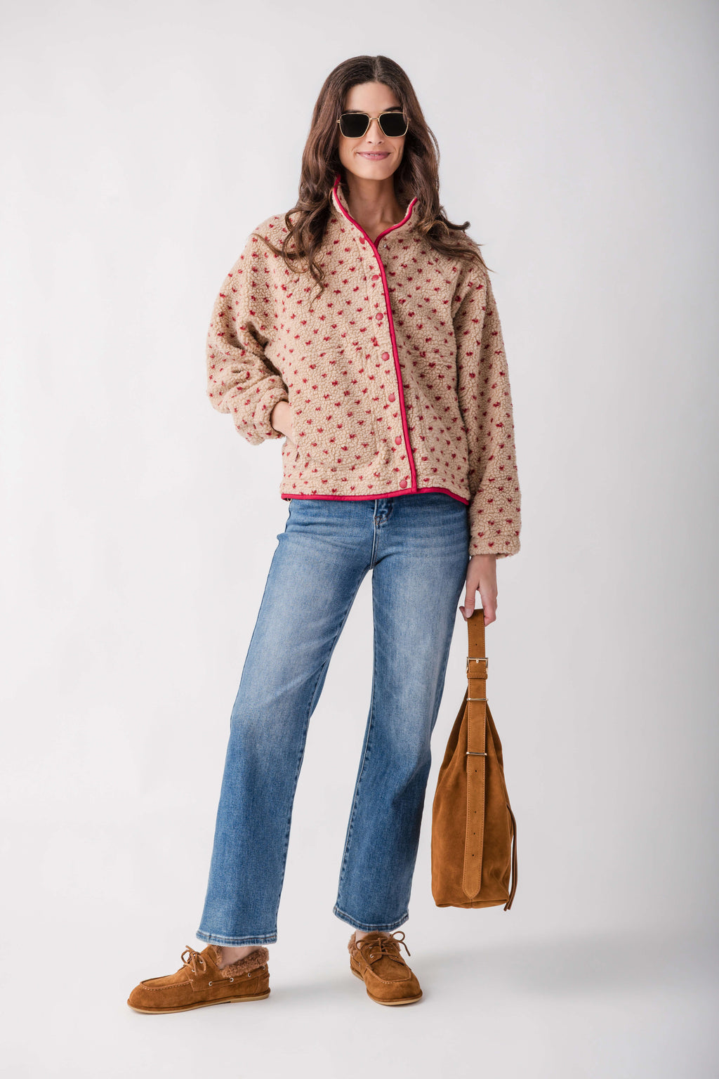 Brown suede boat shoe with lace-up front and stitched details, styled with jeans and floral jacket.