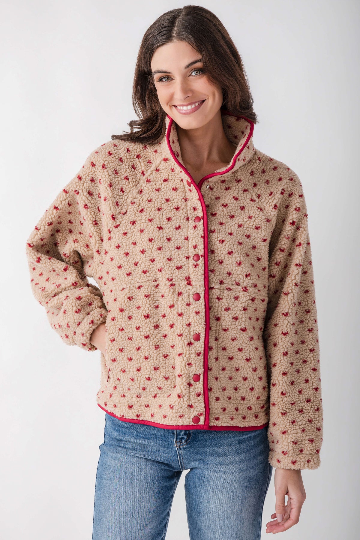Beige sherpa fleece jacket with red dot pattern, snap front closure, and pink trim on collar and cuffs.