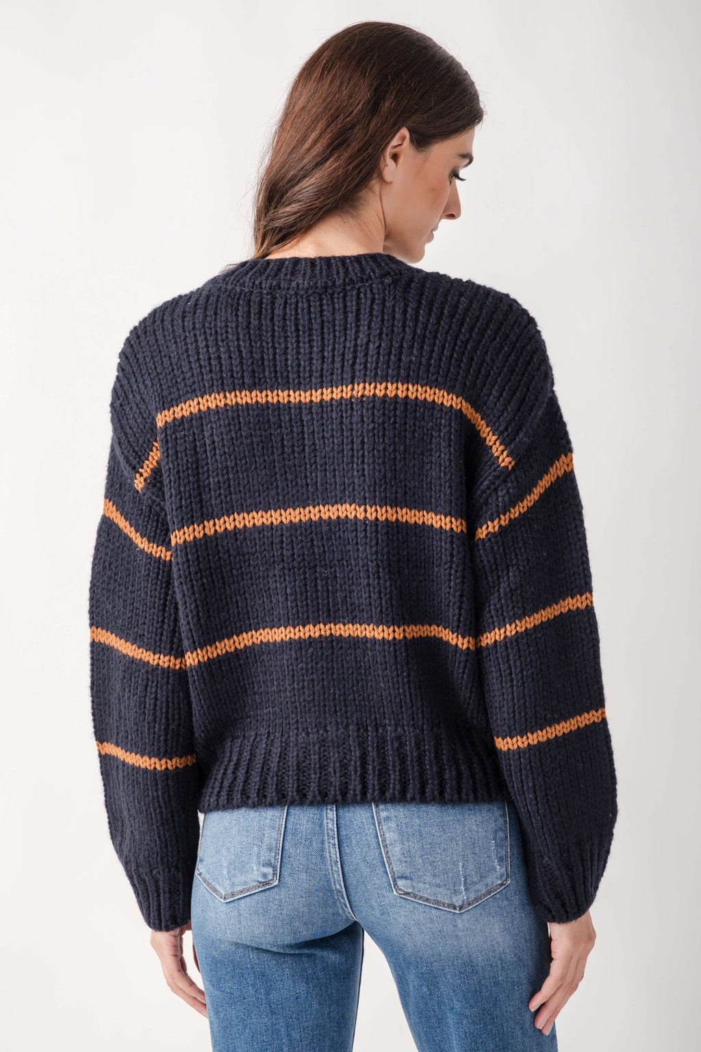 Navy cardigan with horizontal orange stripes, ribbed knit texture, worn over light blue jeans.
