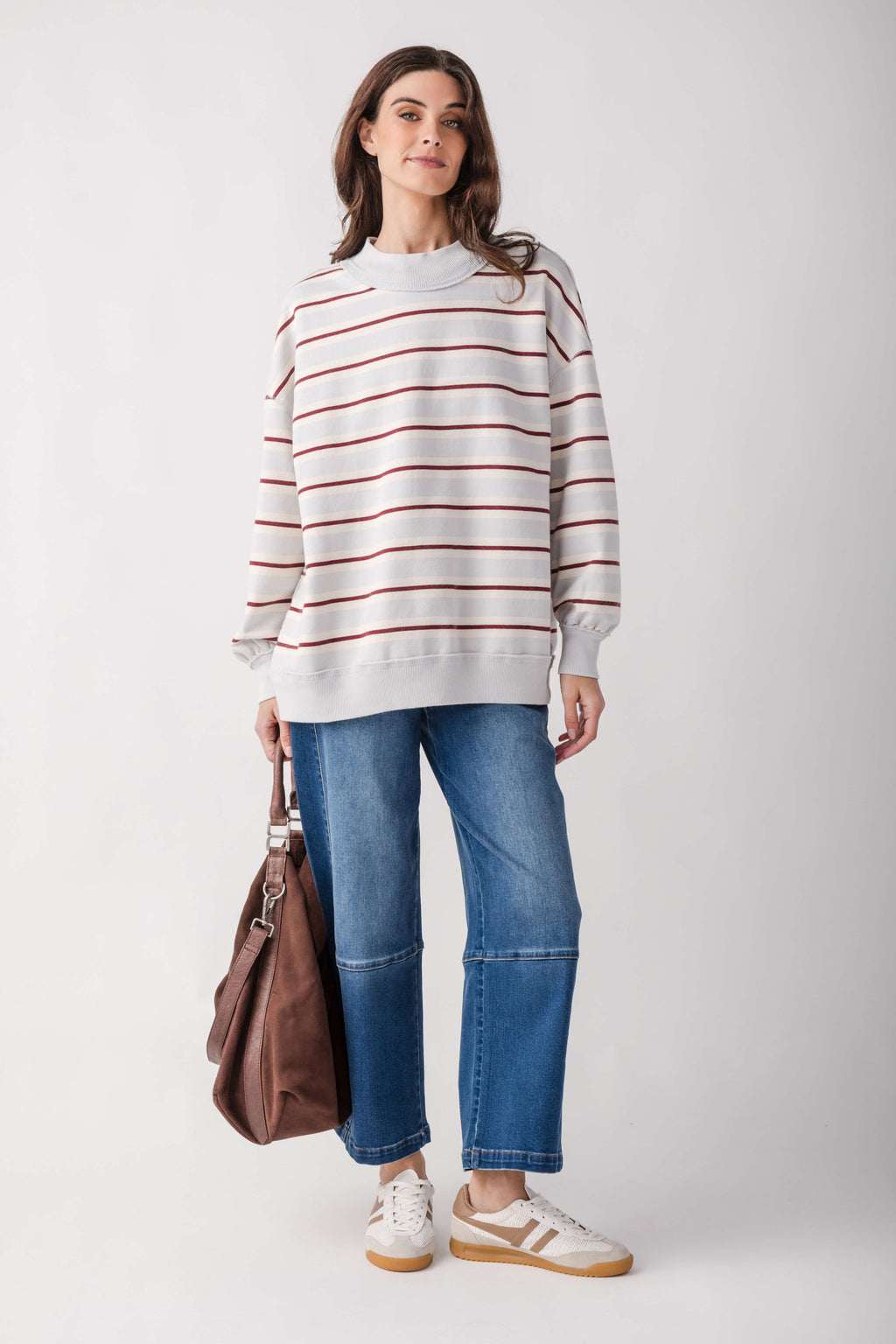 Cream and burgundy striped pullover with crew neck and long sleeves on model wearing blue jeans.