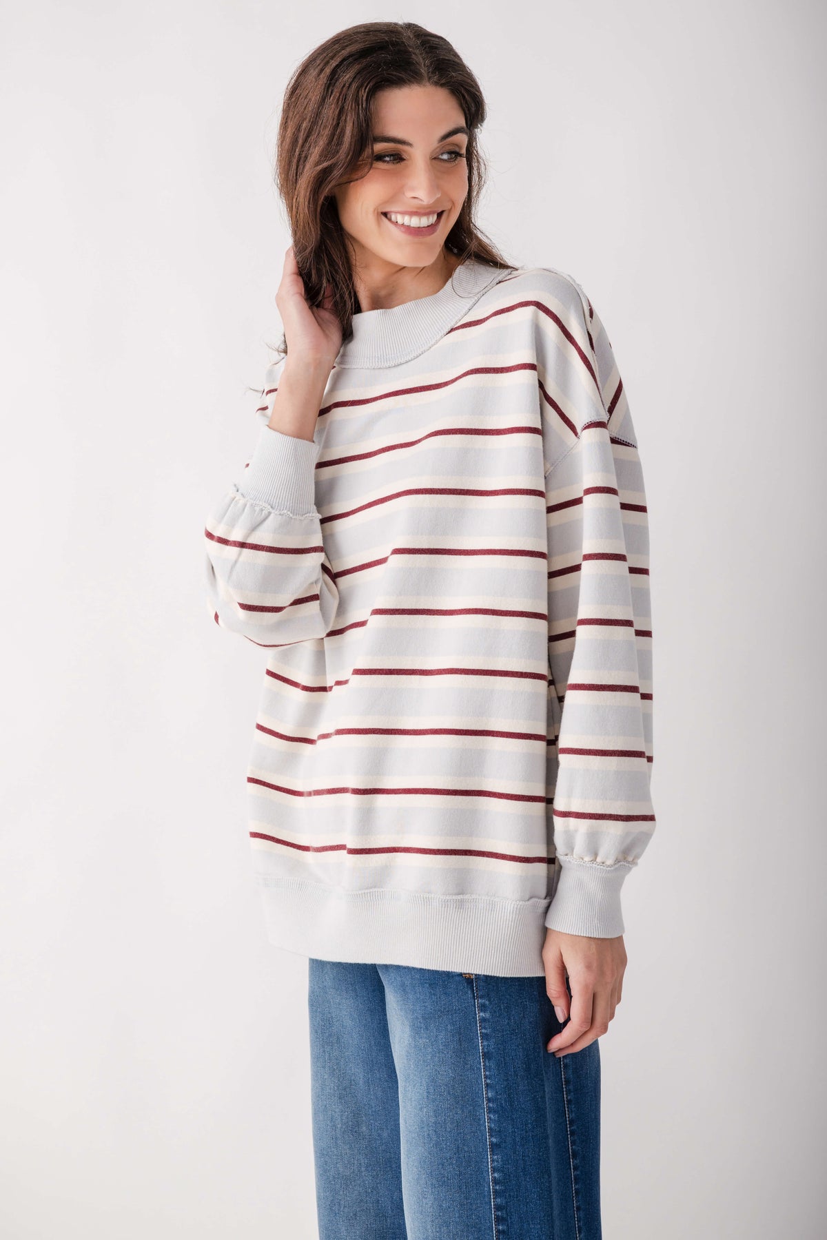 Cream pullover with burgundy horizontal stripes and puffed sleeves, worn with blue jeans.