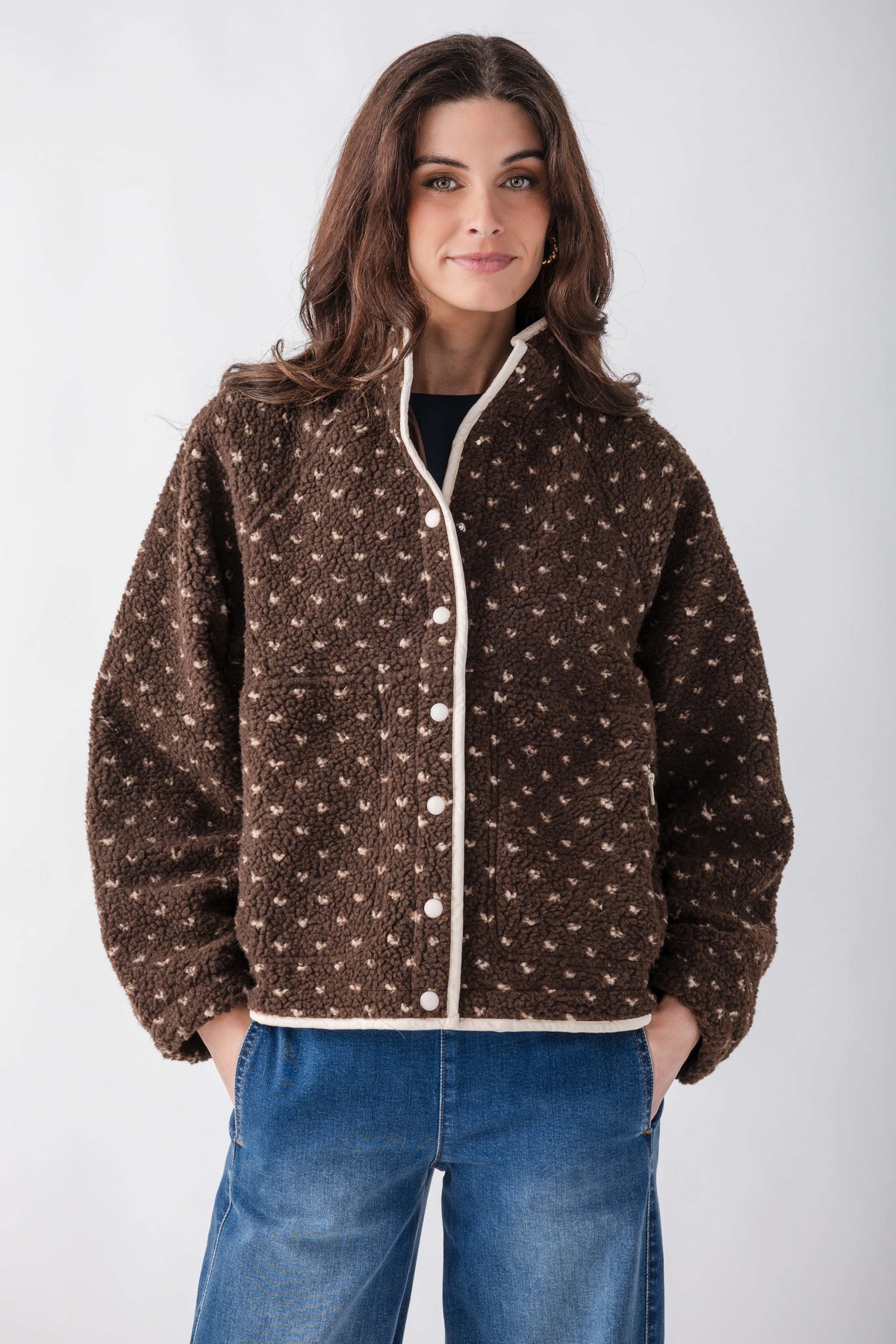 Brown sherpa fleece jacket with allover dot pattern and white snap closures, worn with blue jeans.