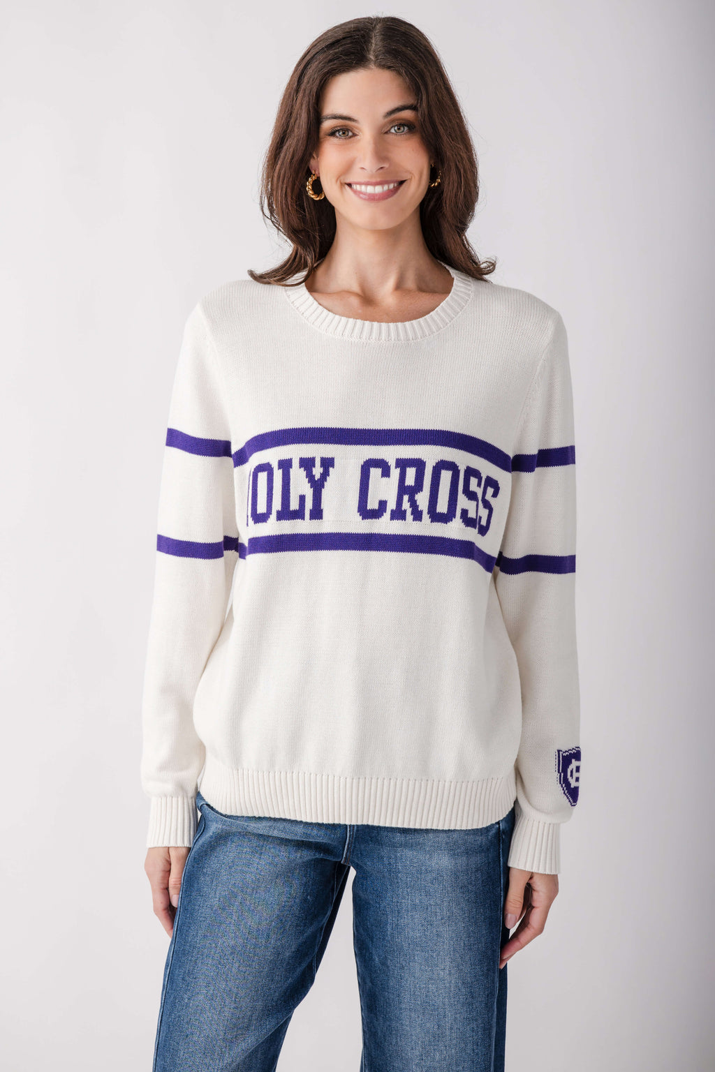 Cream knit sweater with purple "HOLY CROSS" stripe across chest, worn with blue jeans.