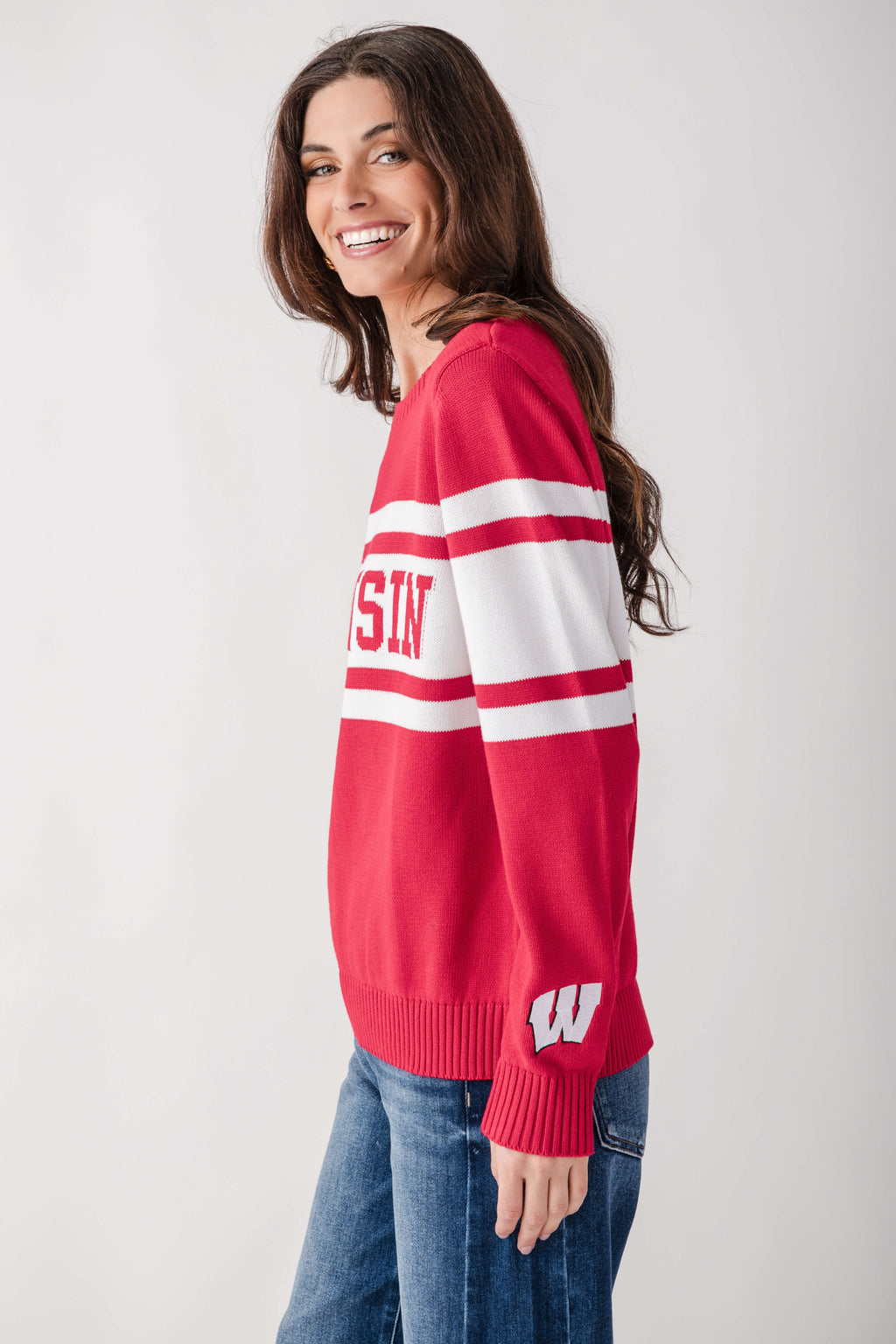 Red and white striped campus sweater with letter and logo details, worn with blue jeans.