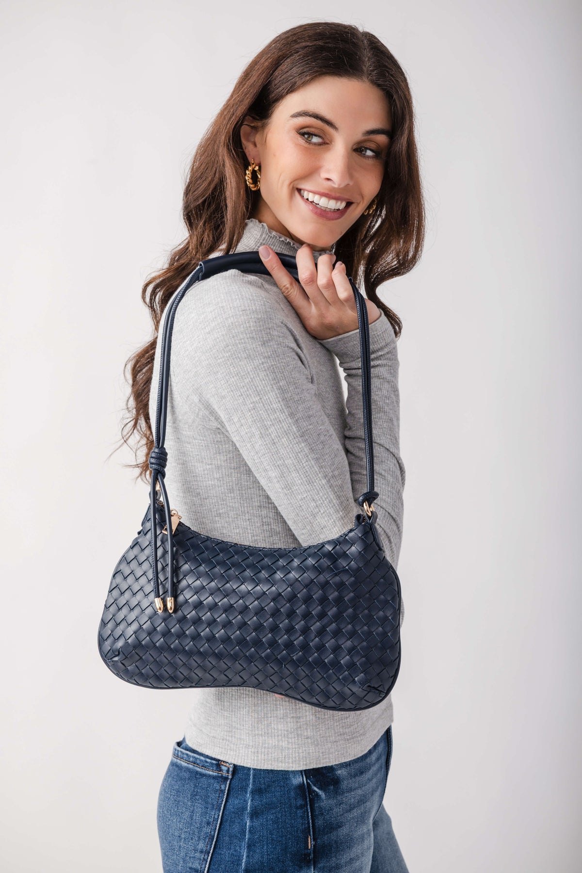 Navy woven leather shoulder bag with adjustable strap worn on model's shoulder.