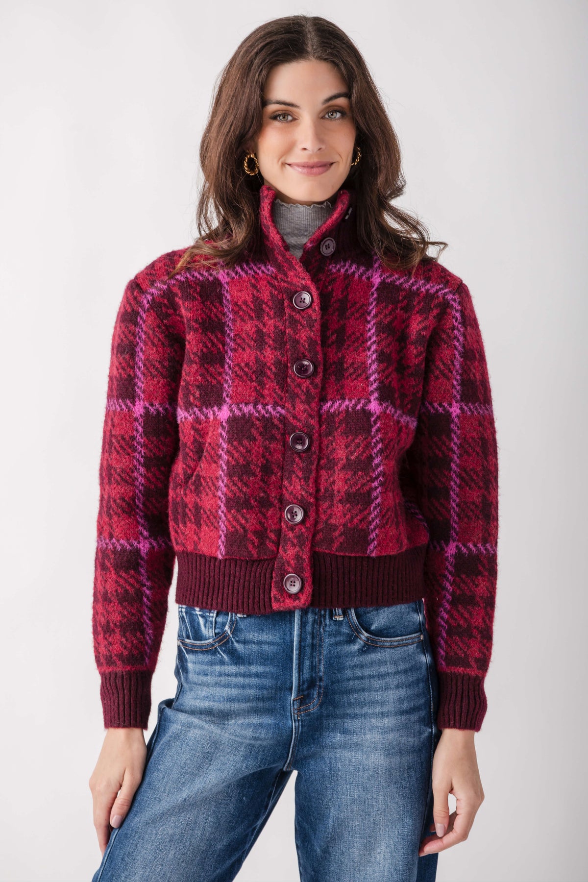 Woman wearing a burgundy plaid mock neck button-front jacket with ribbed cuffs and hem.