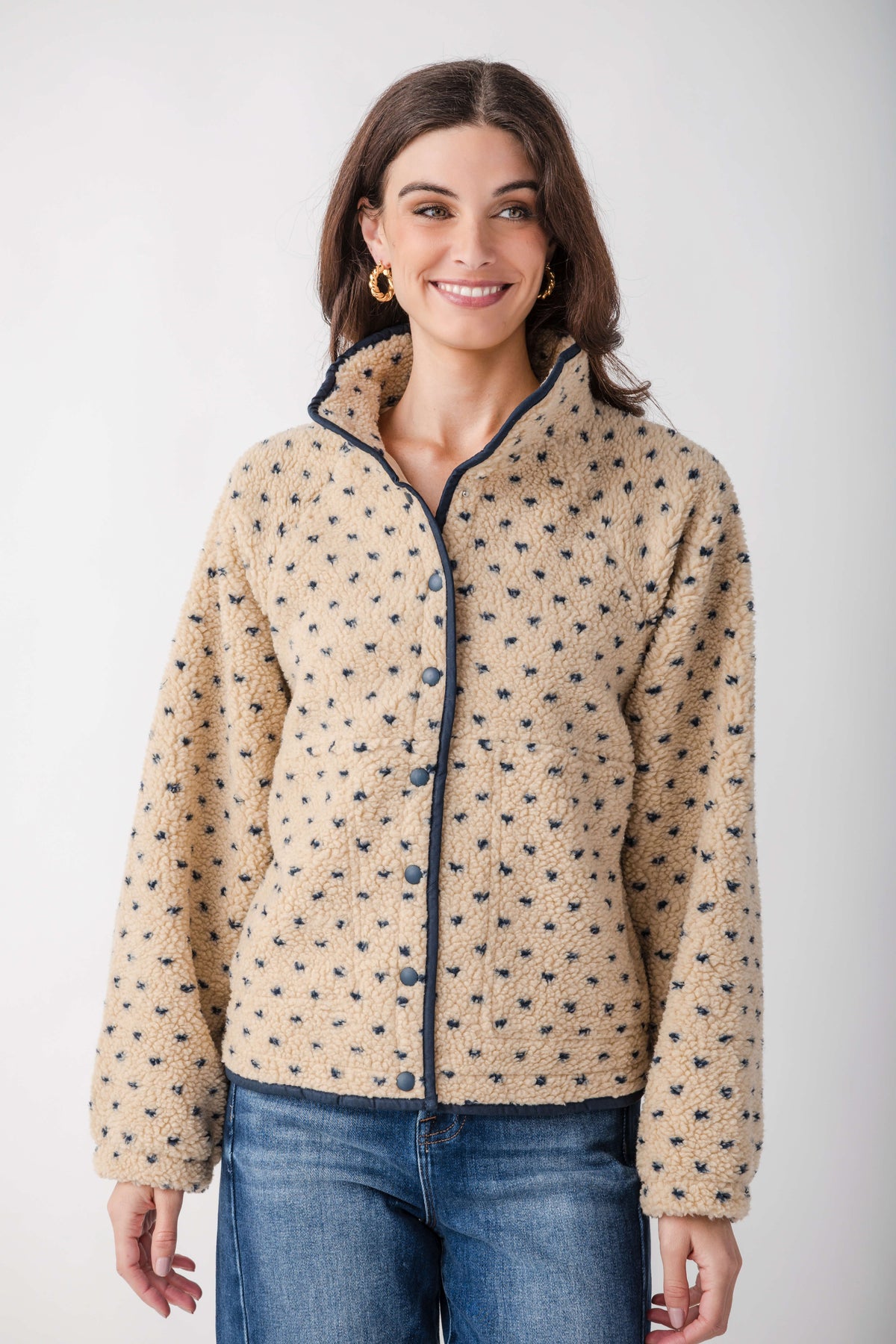 Cream sherpa fleece jacket with small navy dots throughout, navy trim on collar and front snap closure.