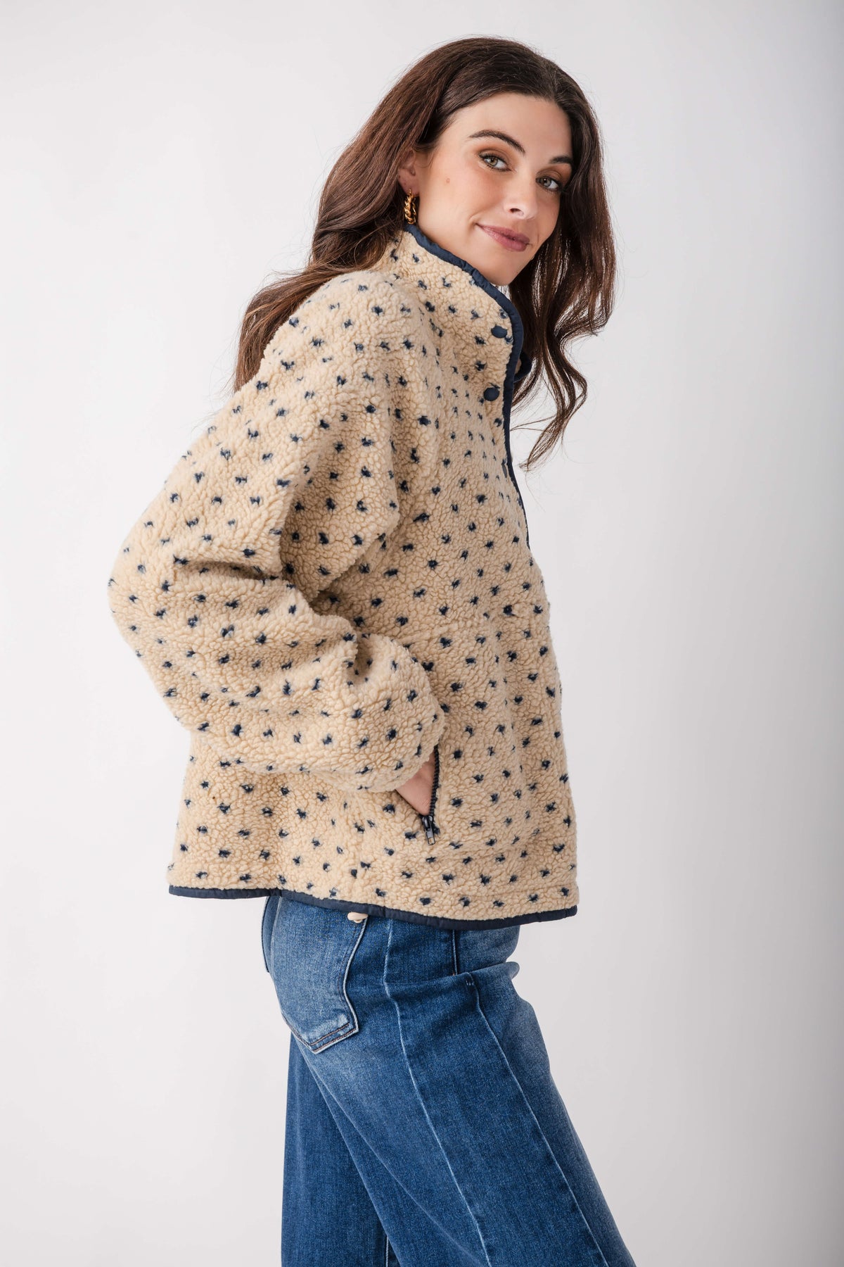Cream fleece jacket with navy dot pattern, navy trim, and snap front closure, styled with jeans.