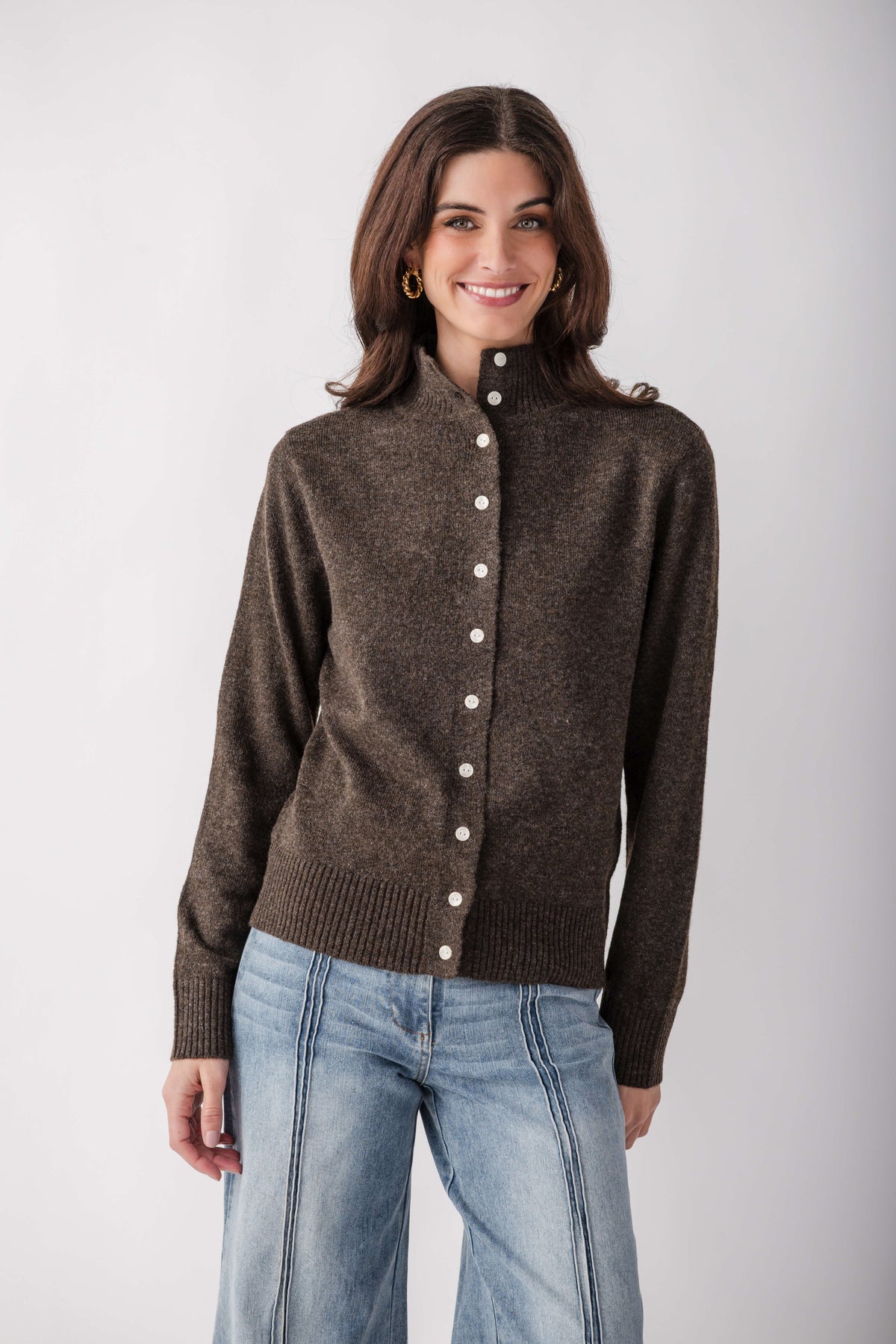 Brown ribbed cardigan with mock neck and white buttons, worn with light blue jeans.