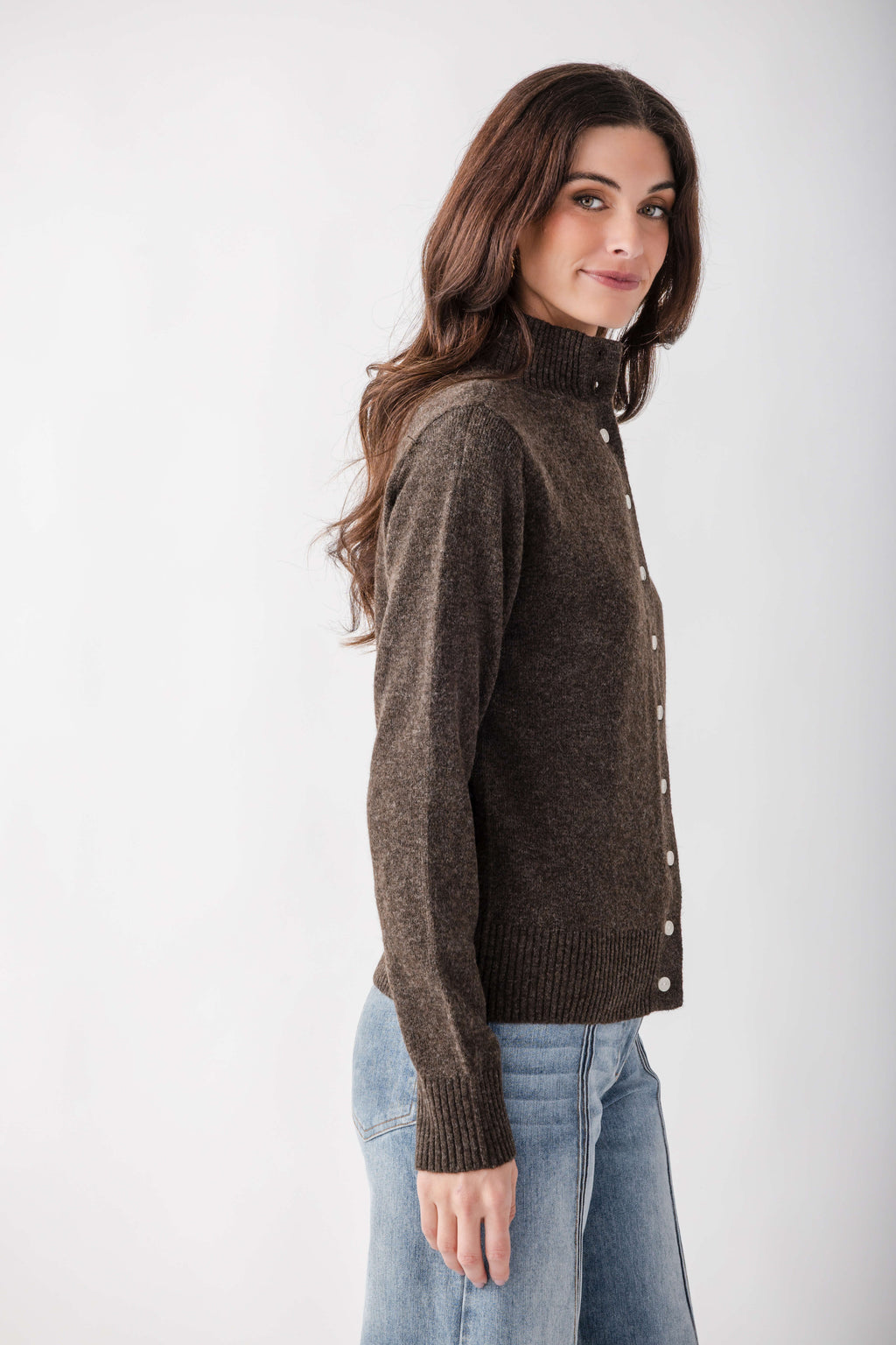 Brown mock neck cardigan with white button front closure and ribbed cuffs, paired with light blue jeans.