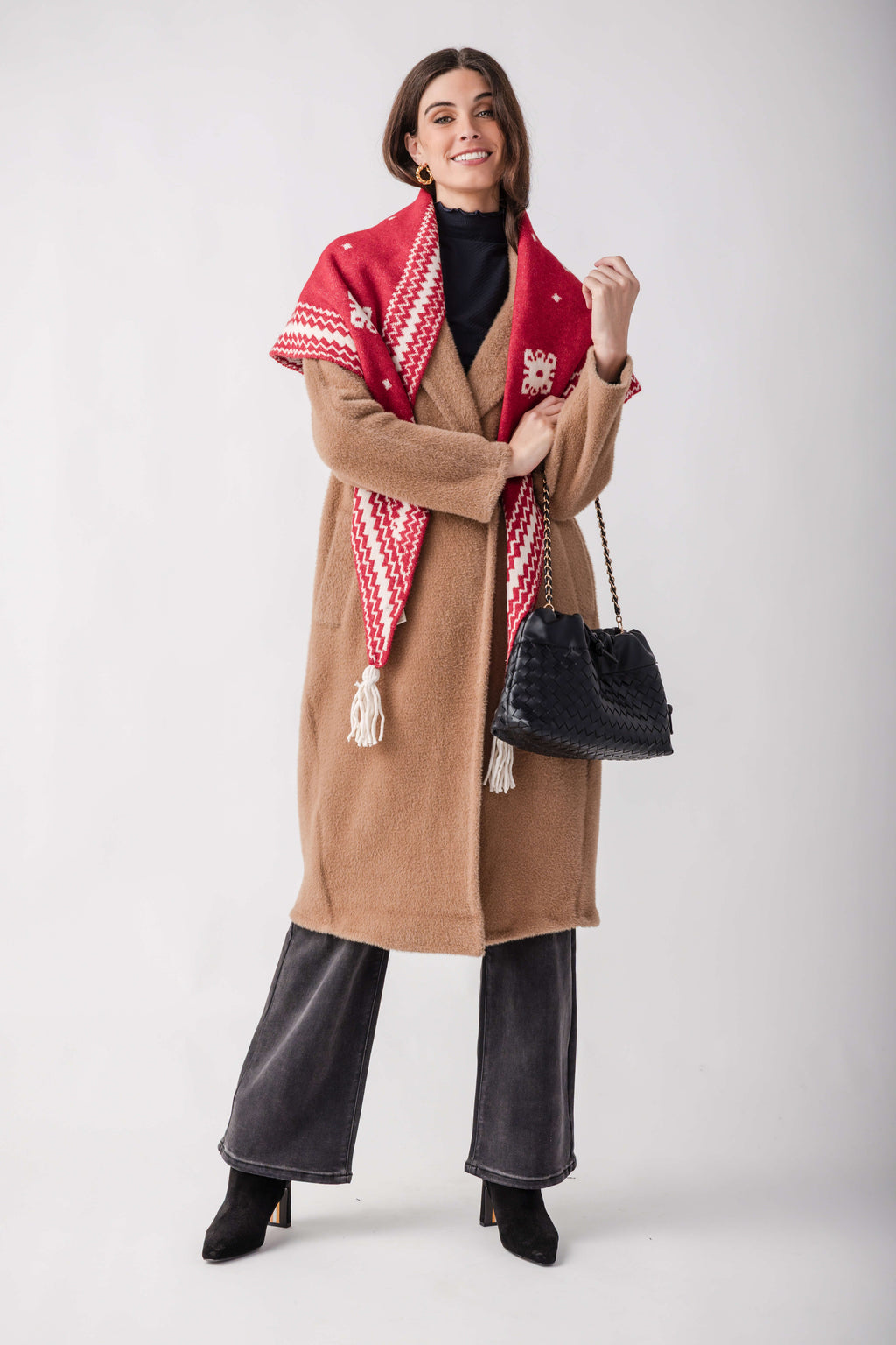 Tan wool coat with red and cream patterned shawl collar, worn over black turtleneck and denim.