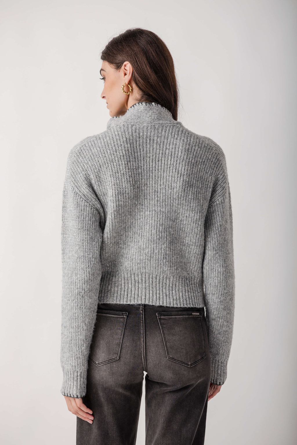 Gray ribbed turtleneck sweater with cropped silhouette worn with dark denim jeans, back view.