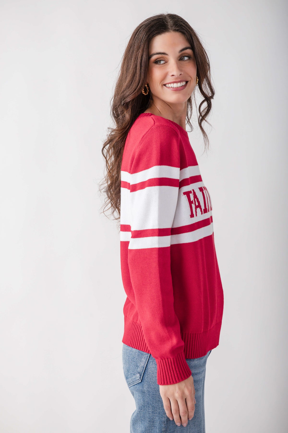 Red and white striped knit sweater with varsity lettering on sleeve, worn with blue jeans.