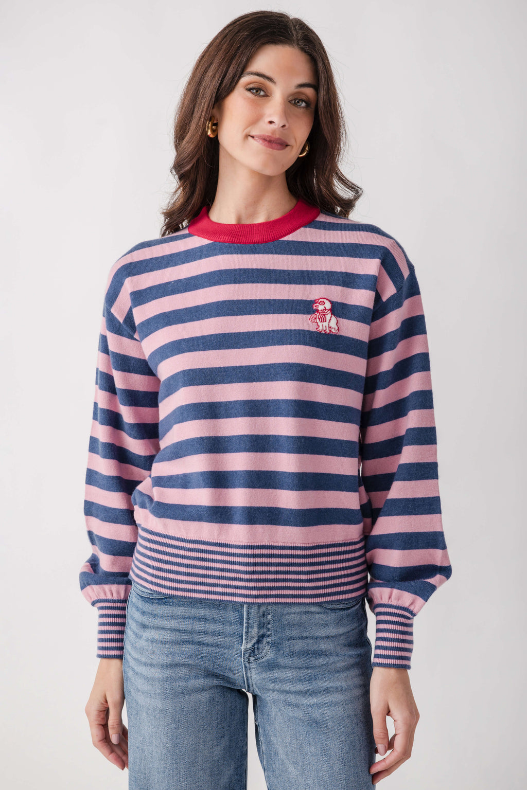 Woman wearing a striped pink and navy sweater with red crew neck and small dog embroidery on the chest.
