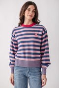 Woman wearing a striped pink and navy sweater with red crew neck and small dog embroidery on the chest.