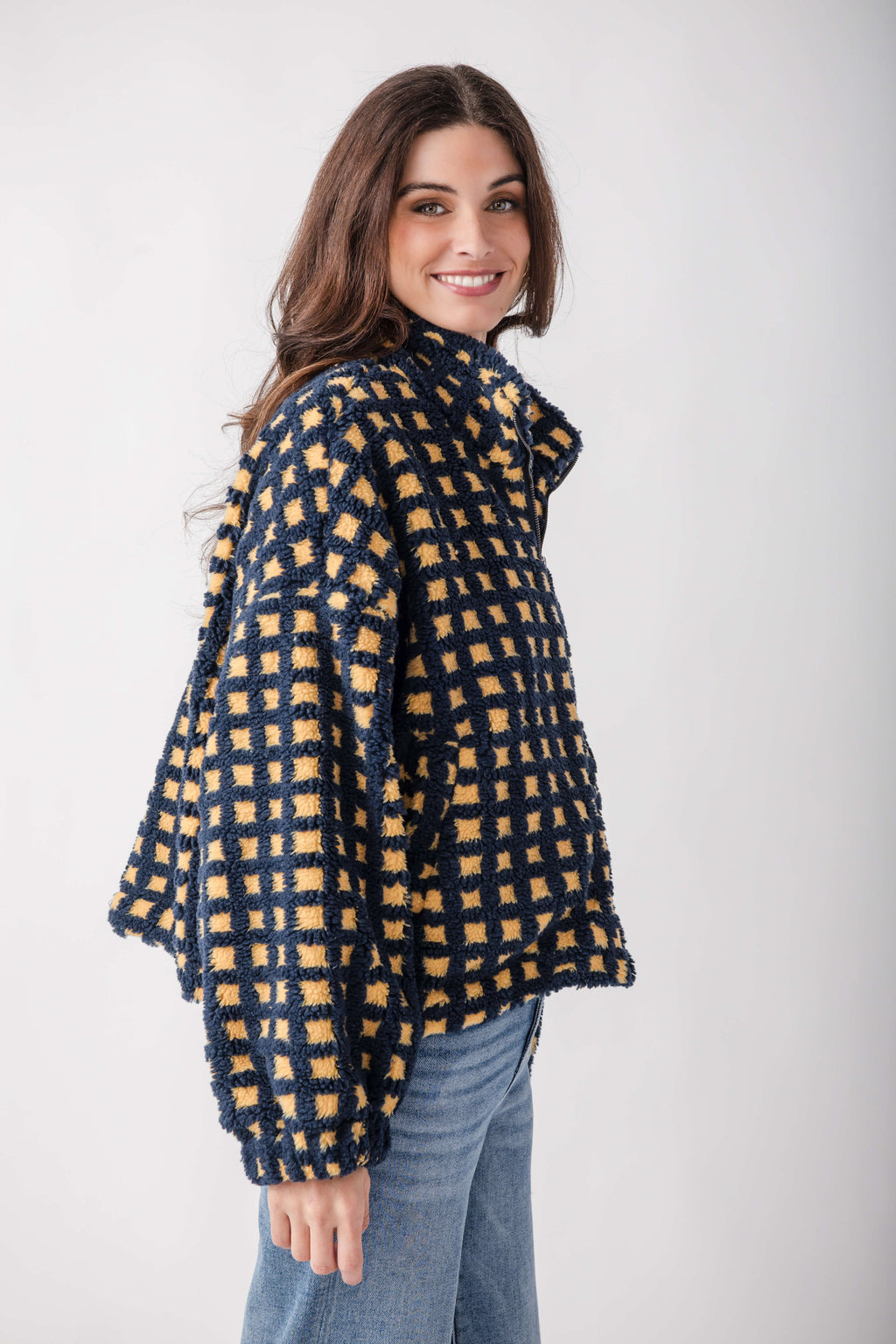 Navy and golden yellow checkered sherpa fleece jacket worn over jeans.
