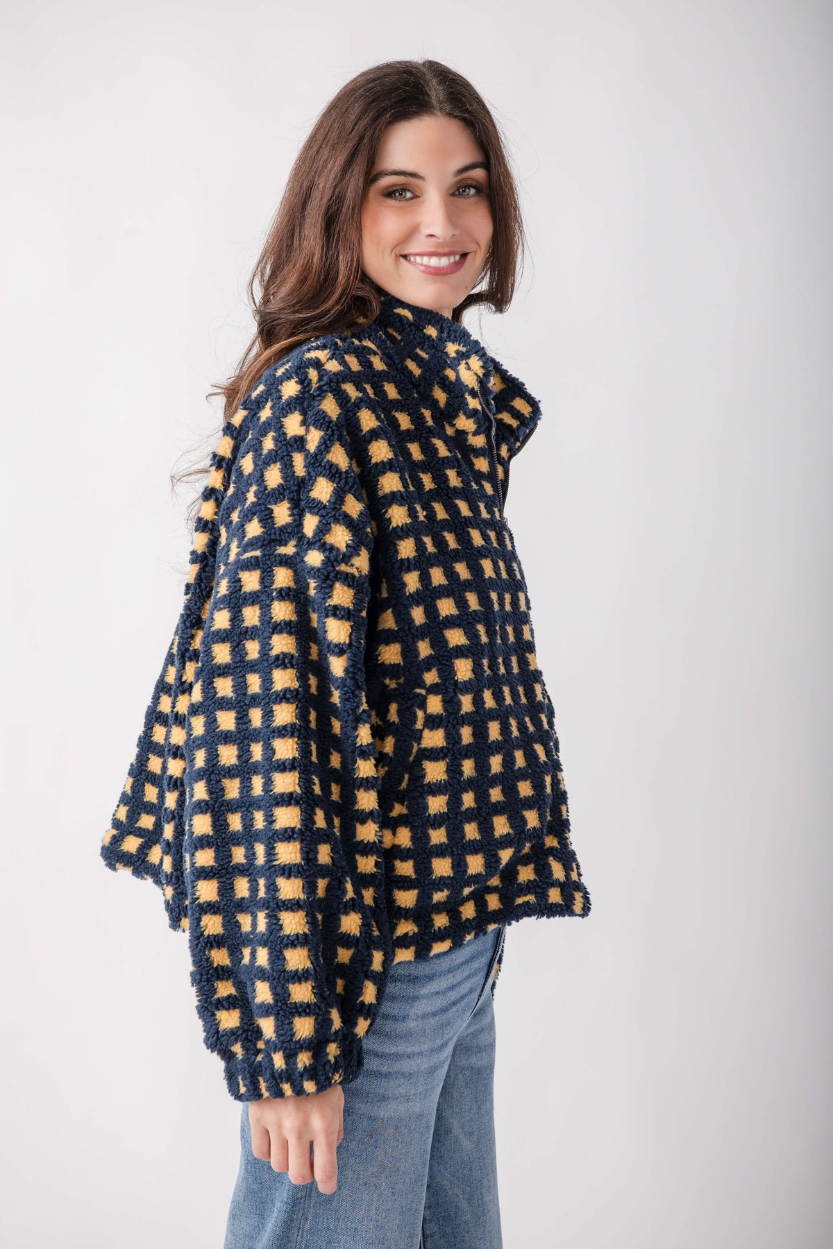 Navy and golden yellow checkered sherpa fleece jacket worn over jeans.