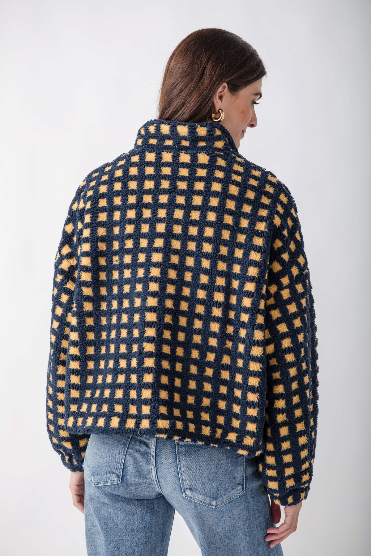 Navy and gold checkered sherpa fleece jacket with full-length sleeves, worn over blue jeans.