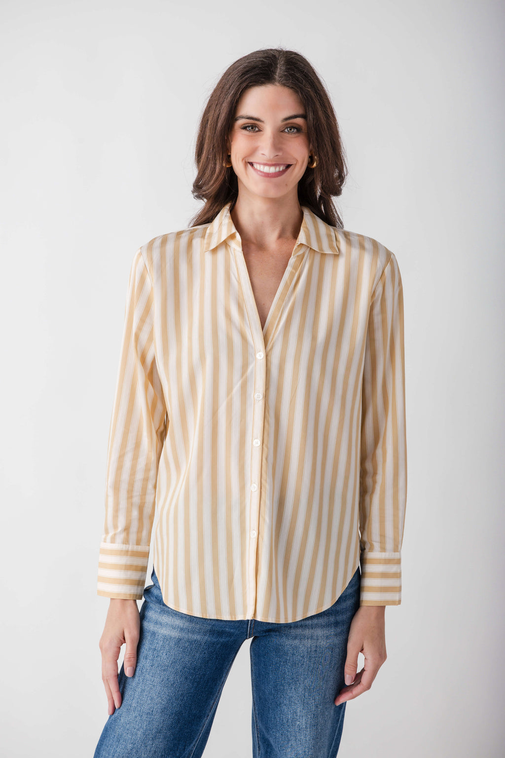 Tan and white striped button-up shirt with long sleeves and pointed collar, worn with blue jeans.