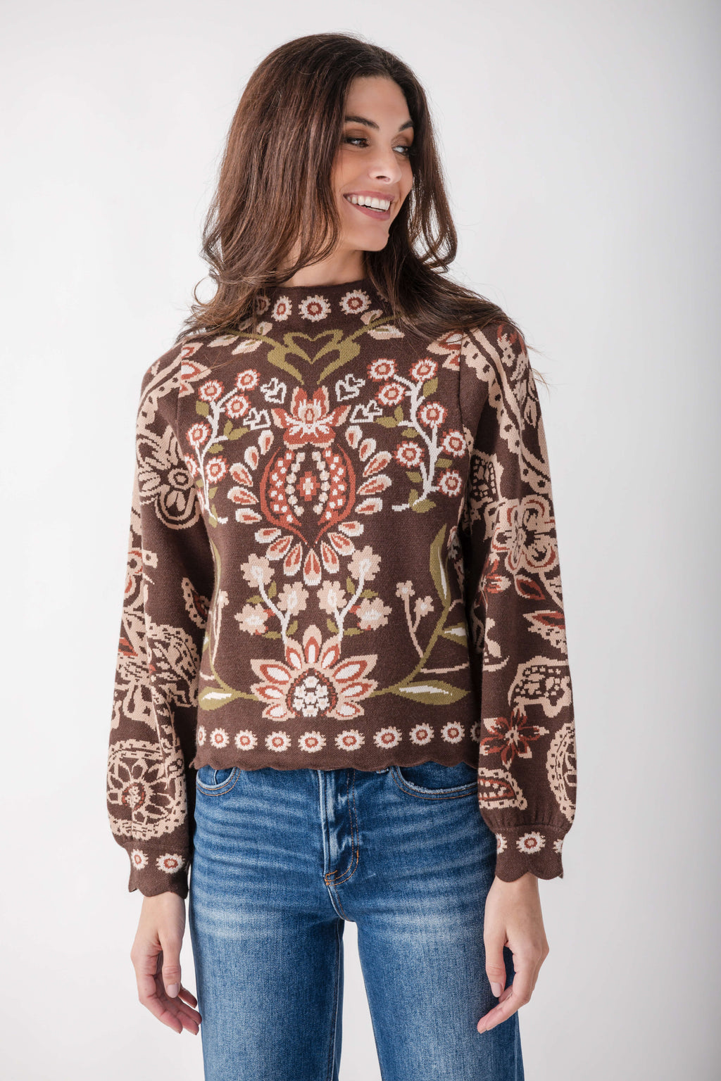 Brown sweater with red, cream, and olive floral and geometric print, scalloped hem, long sleeves.
