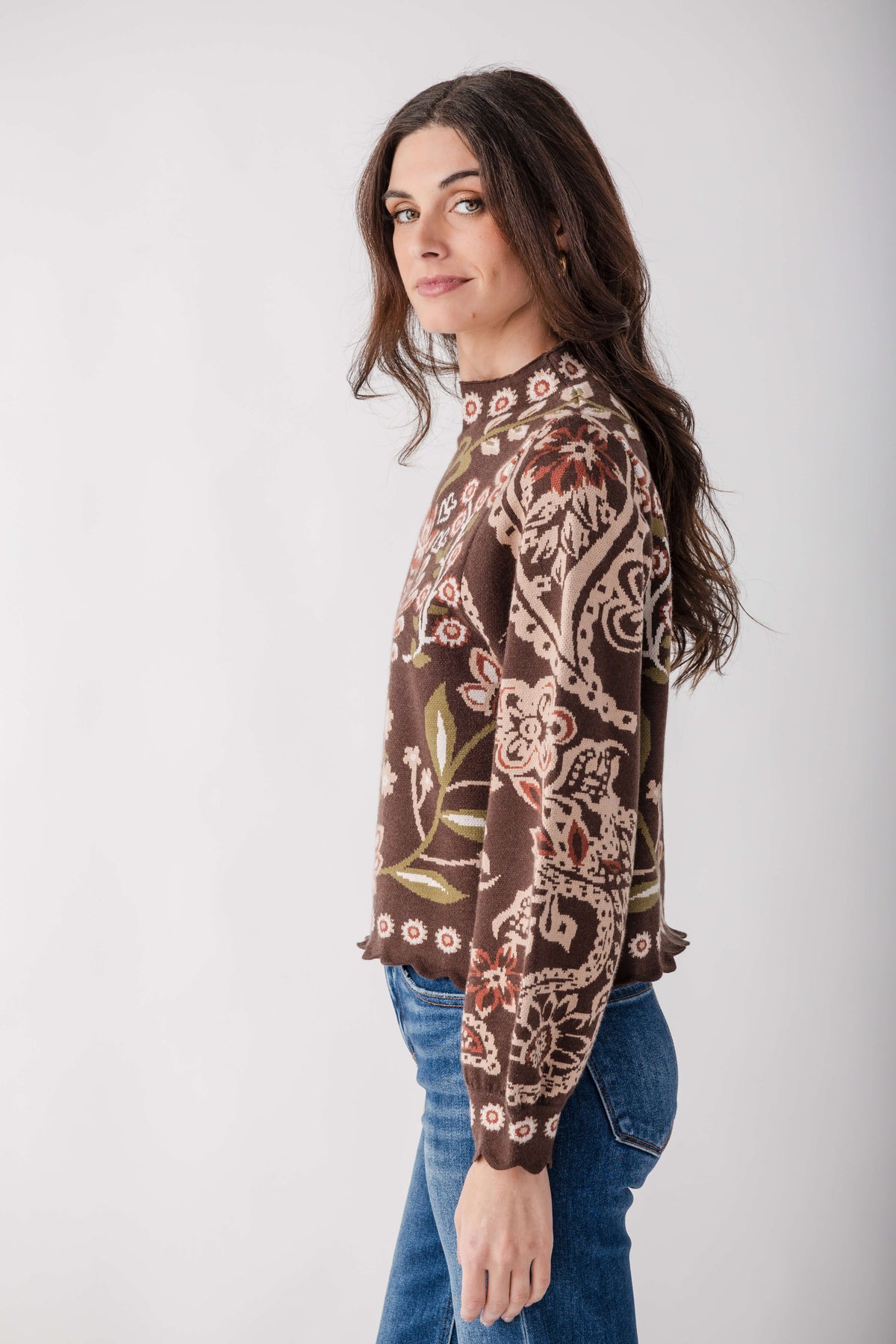 Brown sweater with cream and rust floral print, scalloped hem detail, worn with blue jeans.