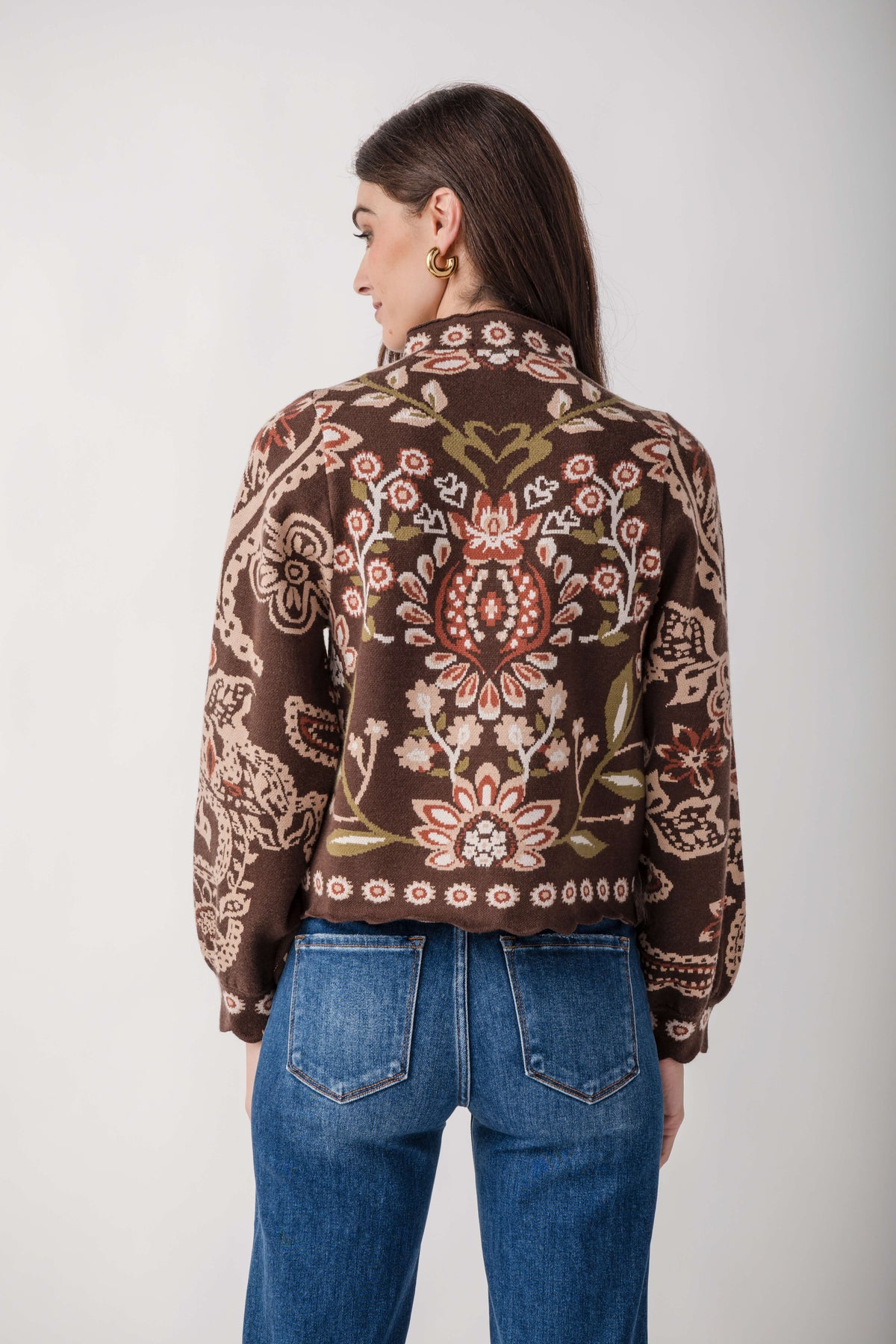 Brown sweater with multicolored floral print and scalloped hem, worn with blue jeans.