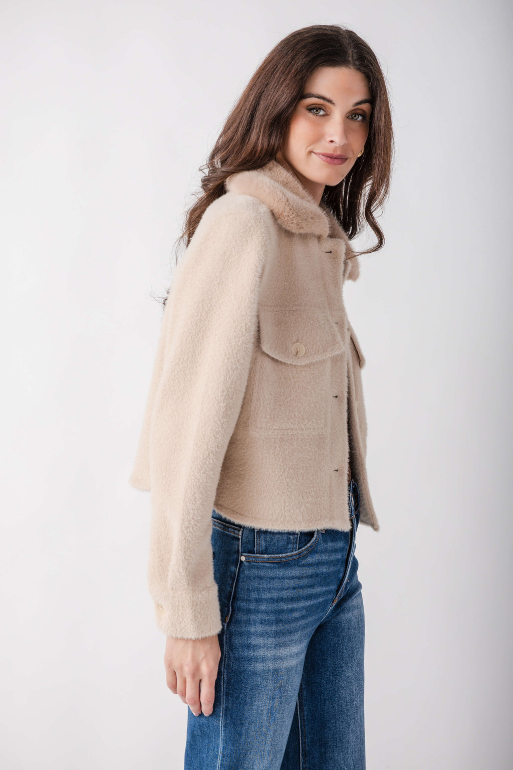 Woman wearing a cream-colored wool jacket with a collar and button front, paired with blue jeans.