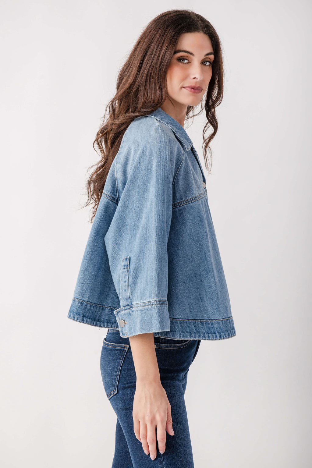 Light blue denim cropped cape jacket with button closure worn over matching jeans.