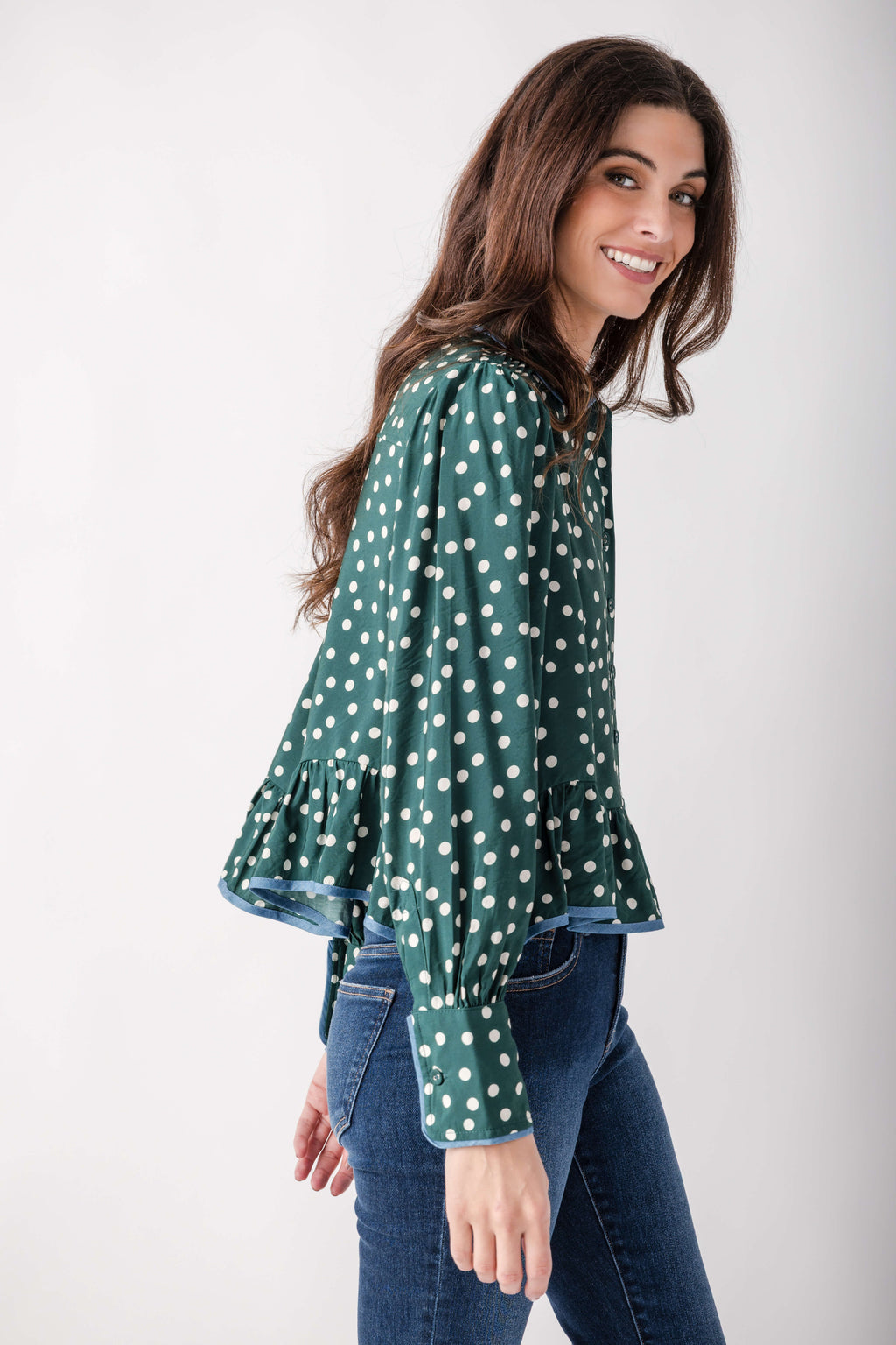 Teal top with white polka dots, Peter Pan collar, and flared sleeves with blue contrast trim, worn with jeans.