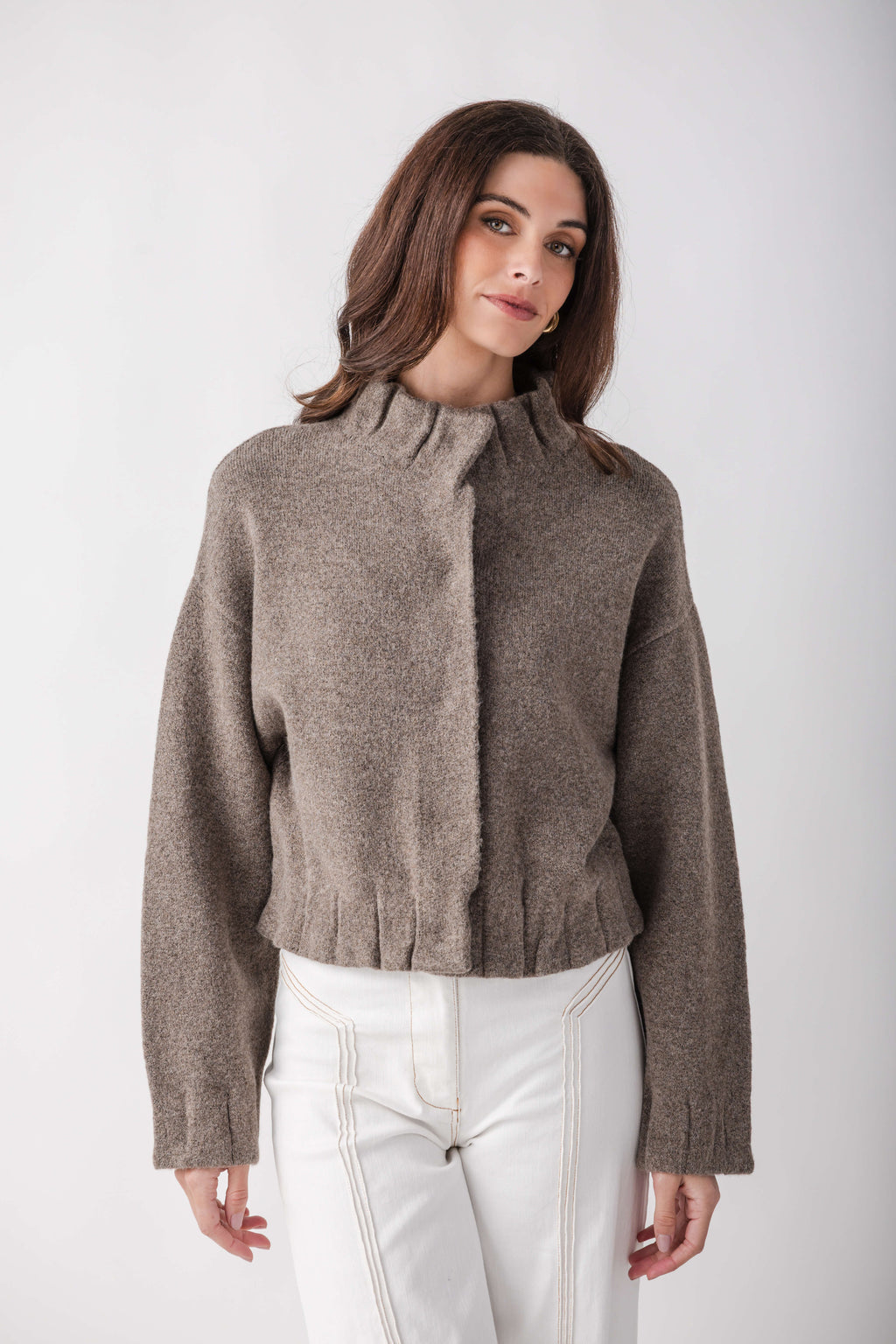 Taupe knit jacket with pleated ruffle detail at center front and cuffs, cropped length, worn with white pants.