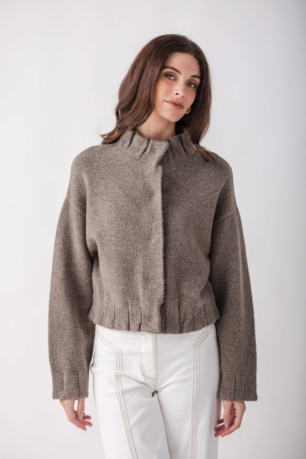 Taupe knit jacket with pleated ruffle detail at center front and cuffs, cropped length, worn with white pants.