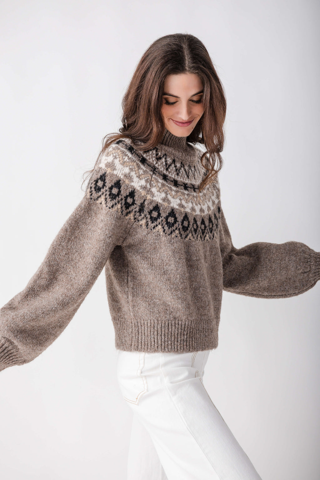 Taupe turtleneck sweater with geometric patterned yoke, paired with white pants.