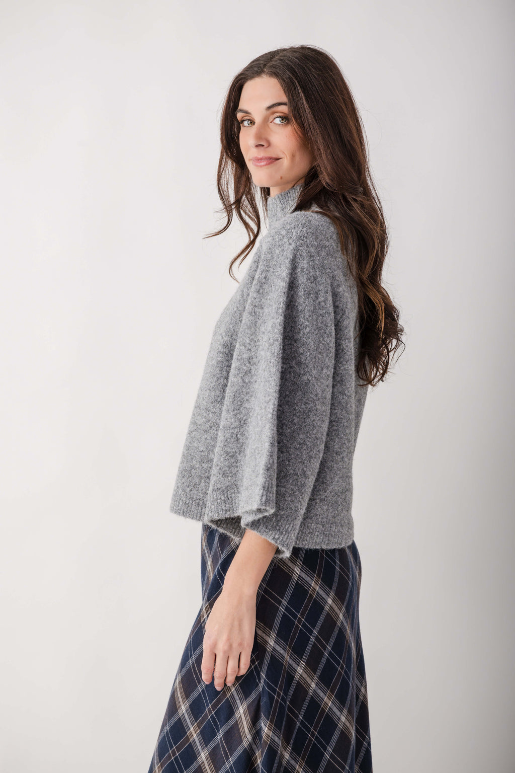 Gray turtleneck sweater with ribbed texture worn with a navy plaid skirt.