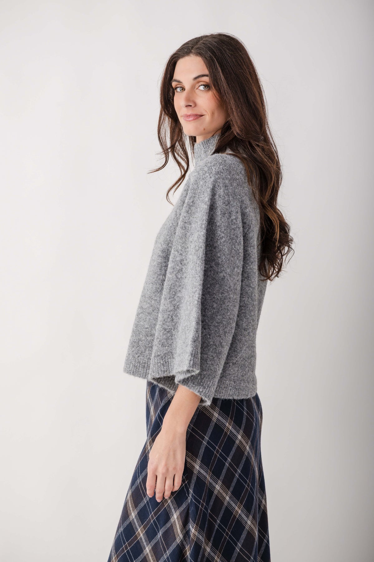 Gray turtleneck sweater with ribbed texture worn with a navy plaid skirt.