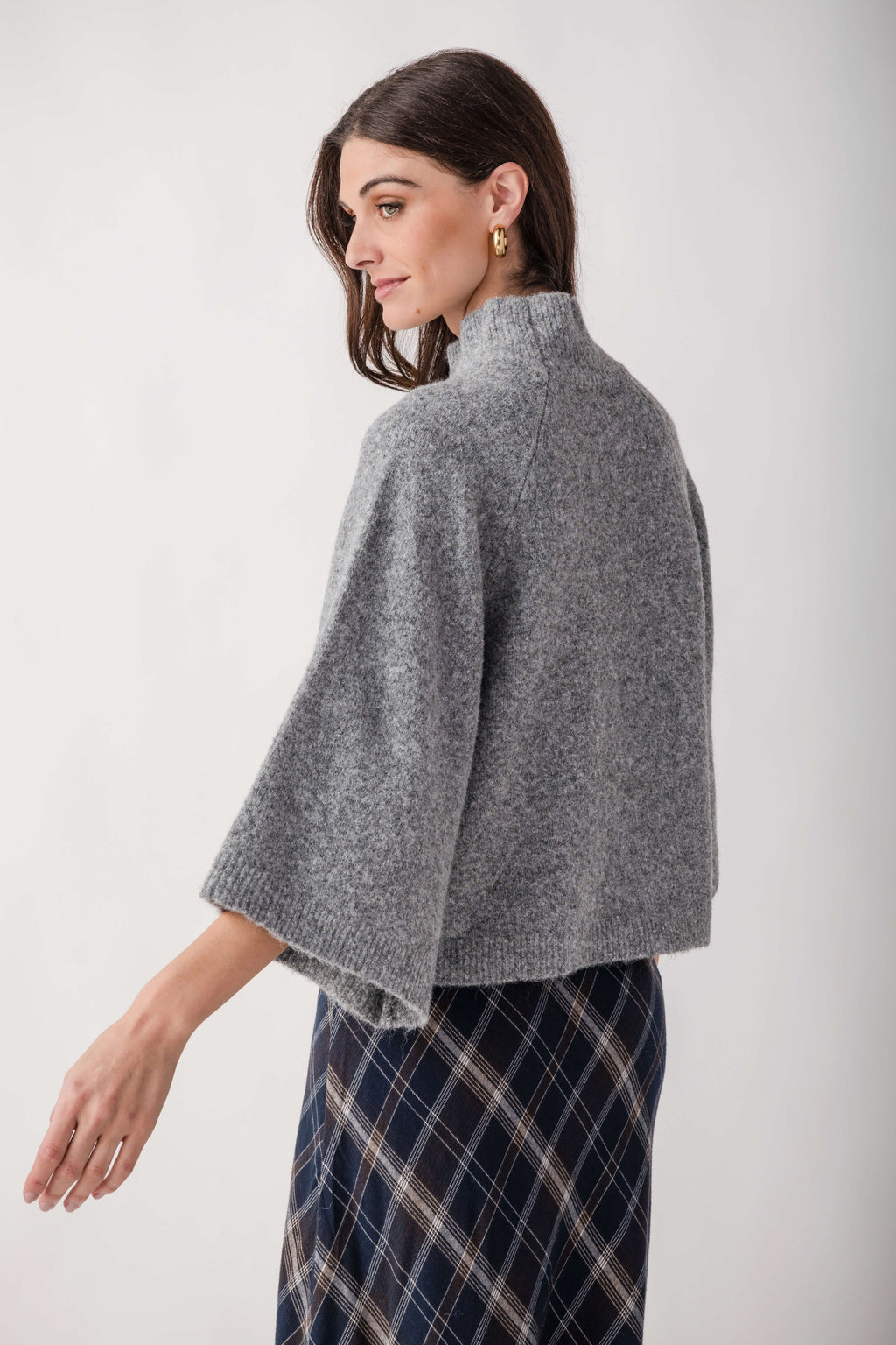 Gray turtleneck sweater with ribbed cuffs and hem, worn with plaid skirt.