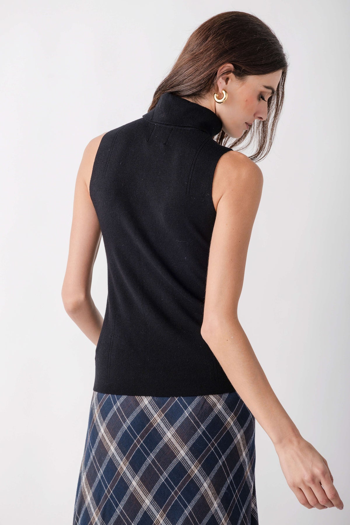 Black sleeveless mockneck top with ribbed texture, shown on model from back view.