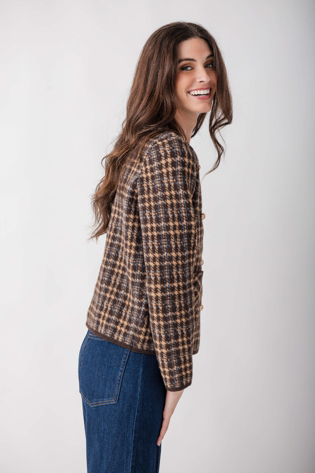 Brown and tan houndstooth tweed blazer with button front worn over blue jeans.