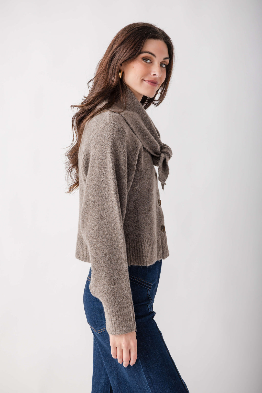 Taupe knit cardigan with detachable scarf wrap, worn with dark blue jeans.