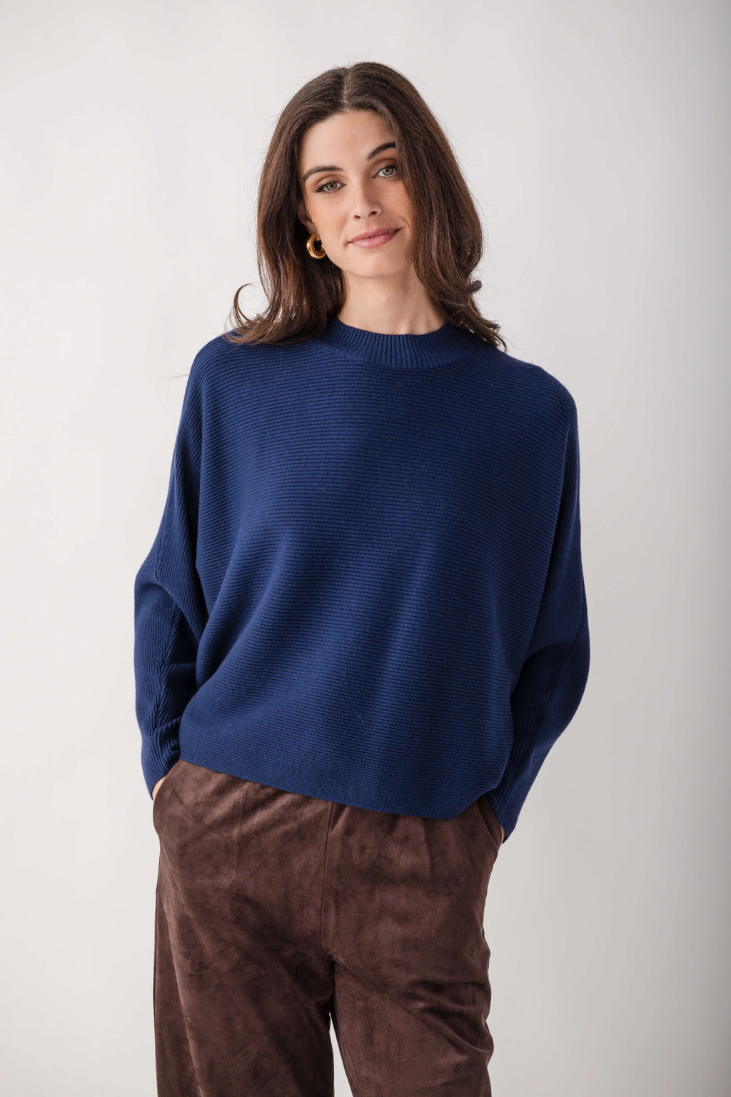 Navy blue crewneck sweater with dolman sleeves and ribbed texture, worn with brown pants.