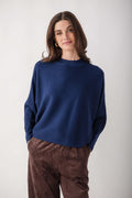 Navy blue crewneck sweater with dolman sleeves and ribbed texture, worn with brown pants.